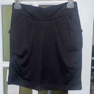 Black knit pencil skirt with pleats and pockets.